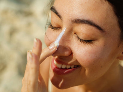 woman applying sun cream to her nose