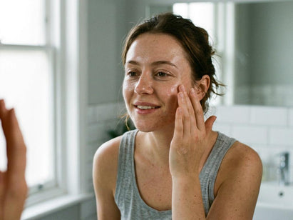 woman in her 20s applying serum to her face