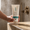 Hand holding white tube of Green People Daily Aloe Conditioner standing on a light bathroom counter next to a running shower in the background