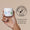 A hand holds a white jar of Organic Babies Soothing Baby Salve next to a Dermatologically Tested logo on a beige background.