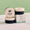 Three round black and beige jars of Green People ONE Balm displayed next to their branded product box on a marble surface.
