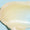 A smooth, glossy swatch of ONE Balm showing its rich, translucent texture against a light blue background.