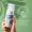 A hand holds a bottle of Oy Clear Skin Foaming Face Wash against a light green background with a Dermatologically Tested badge.
