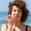 woman by sea applying sun cream to her face image
